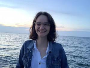 Catherine, wearing a blue jacket and white button down shirt, smiling while standing in front of ...