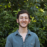 Avi posing outside wearing a blue button-up shirt.