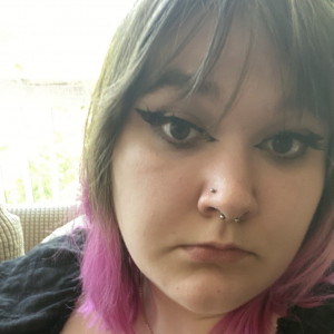 Close up of Maddie. They have brown hair with bangs and dyed pink tips.