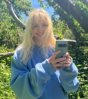 Valerie posing outside wearing a blue long-sleeved sweatshirt.