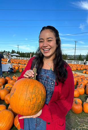 Jodi posing outside in a pumpkin patch.