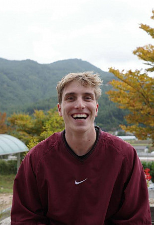 Jonas smiling outside wearing a red sweater.