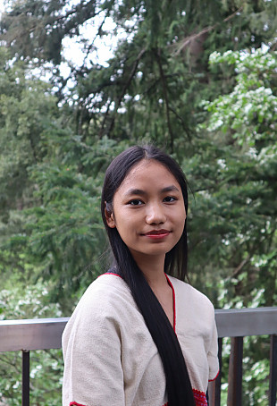 May smiling outside, wearing a white top.