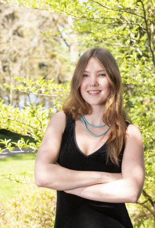 Cadyn posing outside. She is wearing a black tank-top dress.