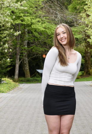 Kaylee posing outside in a white top and black pants.