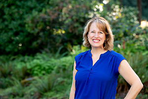 Kathy smiling outside, wearing a blue sleeveless top.