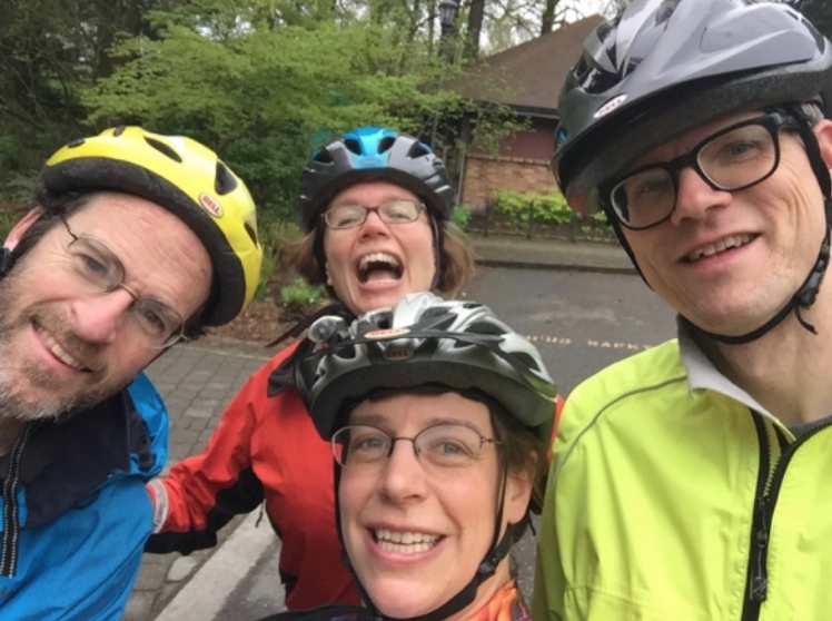 Smiling bike posse members wearing bike helmets.