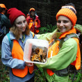 Two people show a bucket of mushrooms they have collected