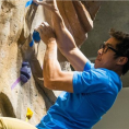 A student climbs up an indoor rock wall