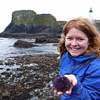 Makayla holding a sea urchin in front of tidepools