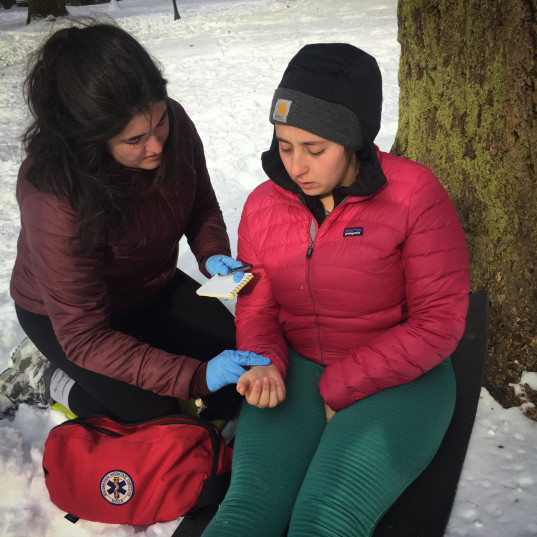 Wilderness First Responder measures the pulse of a patient