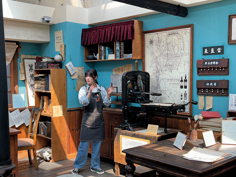 A tour guide describes a printing press at the Book City Letterpress Museum.