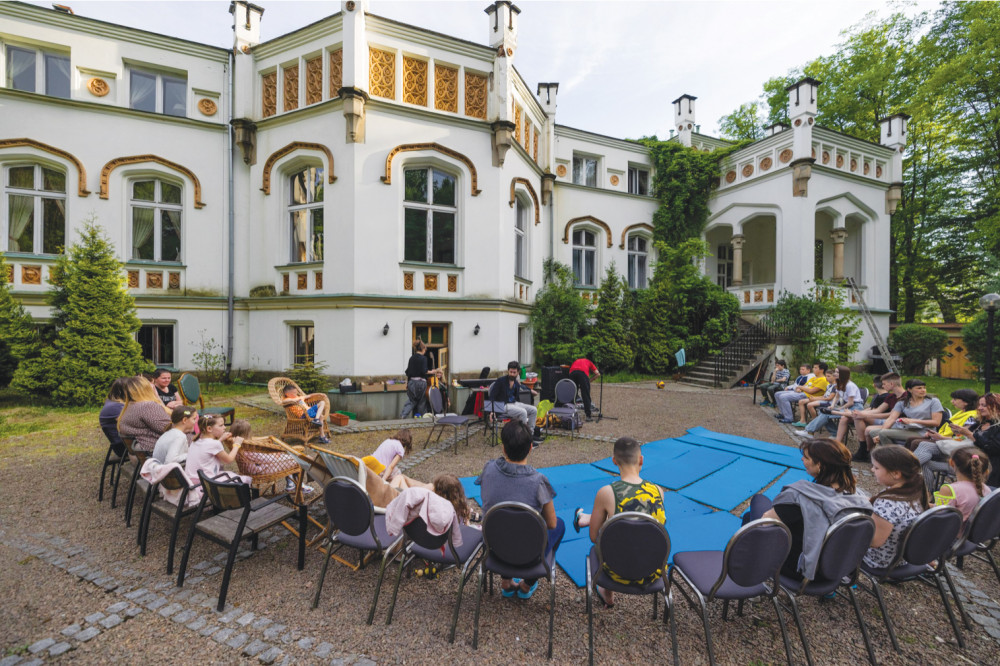 Photo of a large group of people siting outside Paszkowka Palace