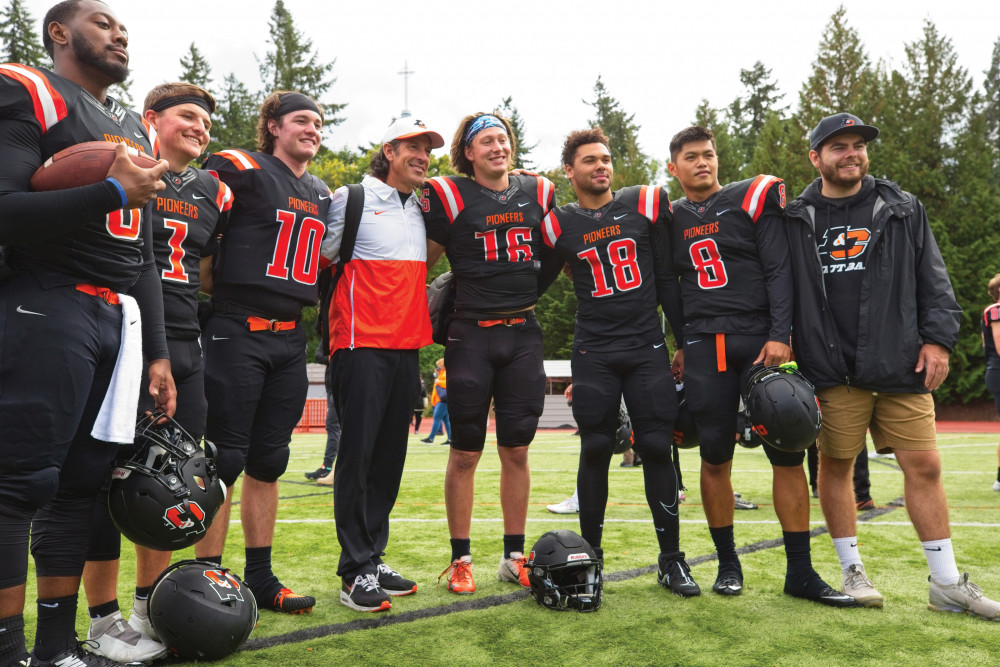 Joe Bushman (center), Lewis & Clark's new head football coach, surrounded by members of the 2022-23 team.