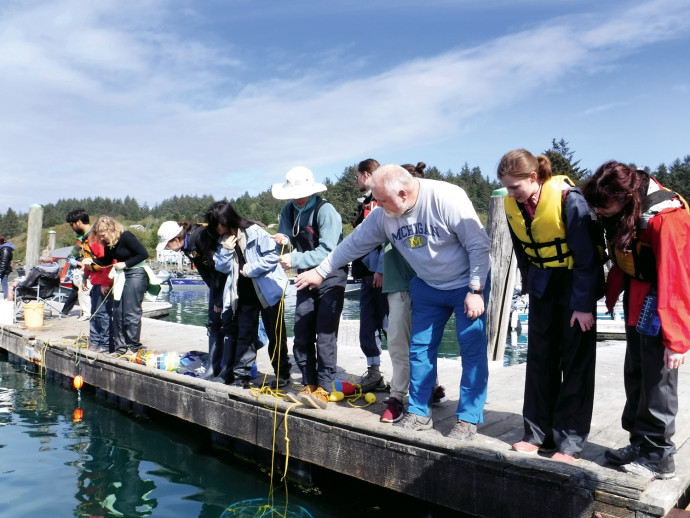 Erik Nilsen, associate professor of psychology, shows students how to bait a crab pot during a crabbing trip to Nehalem Bay. (College Out...