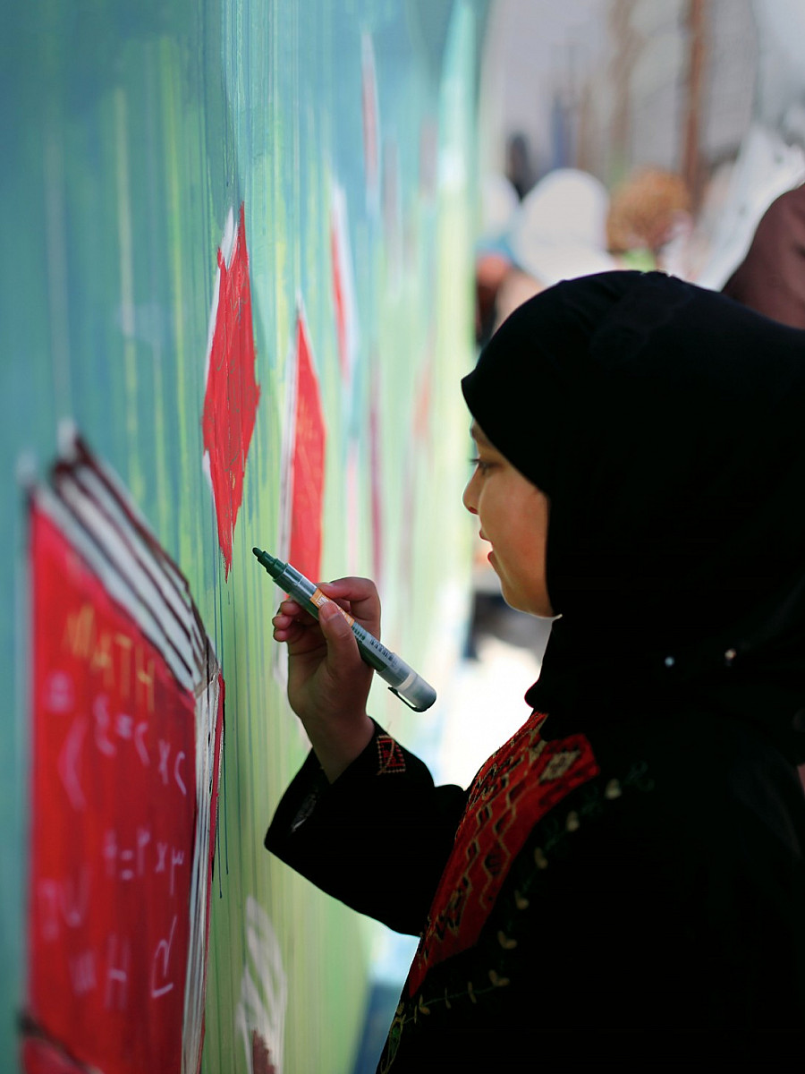 A young Syrian refugee paints a street mural as part of an aptART workshop in the Zaatari refugee camp in Jordan.