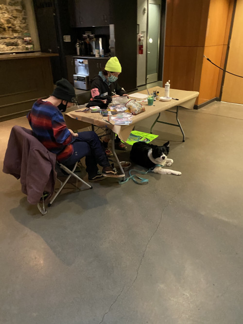 Two supporters paint while their dog lies under the table at the BLM Art Event at The Armory in Portland, Oregon on April 7, 2021.