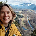 woman with blond hair, yellow jacket, and standing in from a canyon.