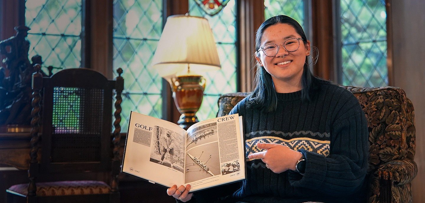 Sophie posing inside the Manor House showing off a book.