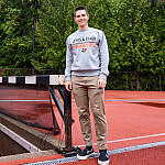 Joseph posing outside near a hurdle on the track.