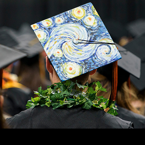 A student with a colorful mortarboard at commencement.