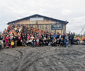 A group photo of the attendees beneath the Arctic Village sign.