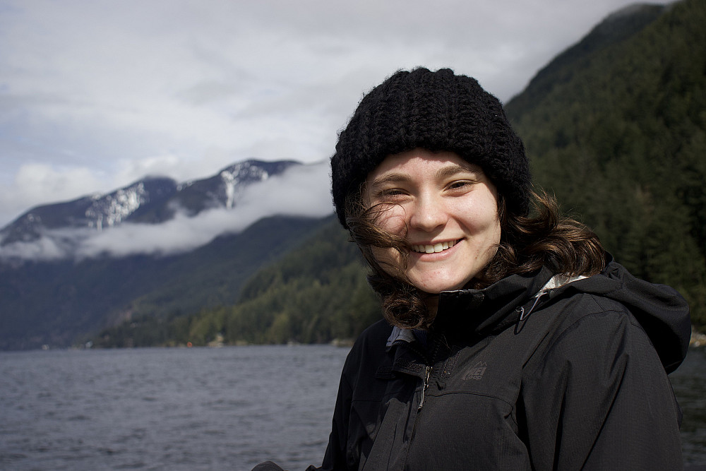 Charley posing in front of a body of water, wearing a dark-colored beanie and jacket.