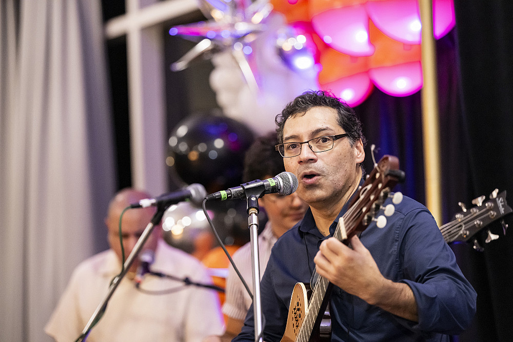 Freddy singing into a microphone while playing a Venezuelan Cuatro.