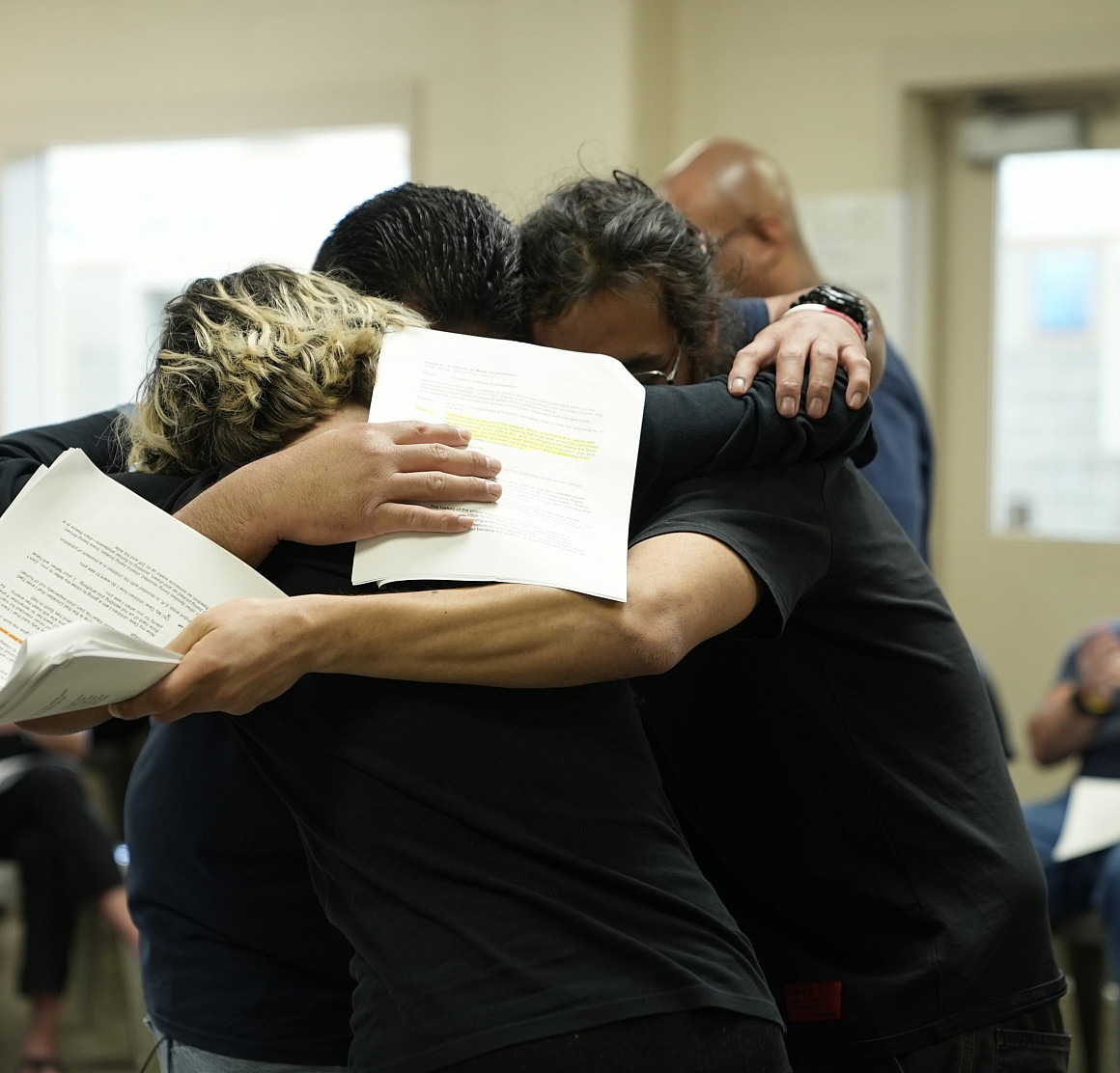Inside and outside students hug in a group.
