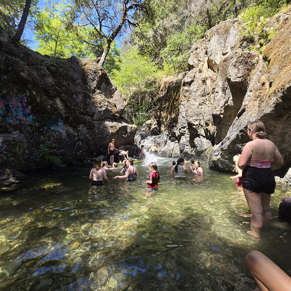 Group of people swimming in a small body of water surrounded by large rocks.