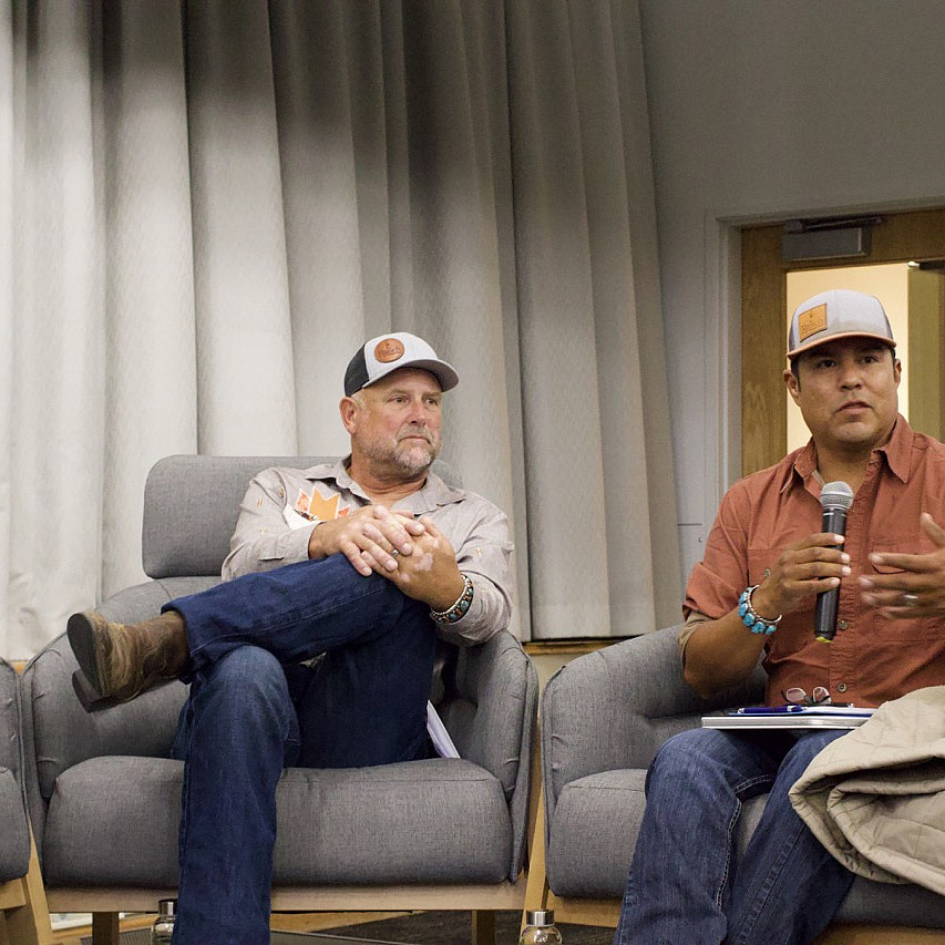 Two people speaking on stage during a panel.