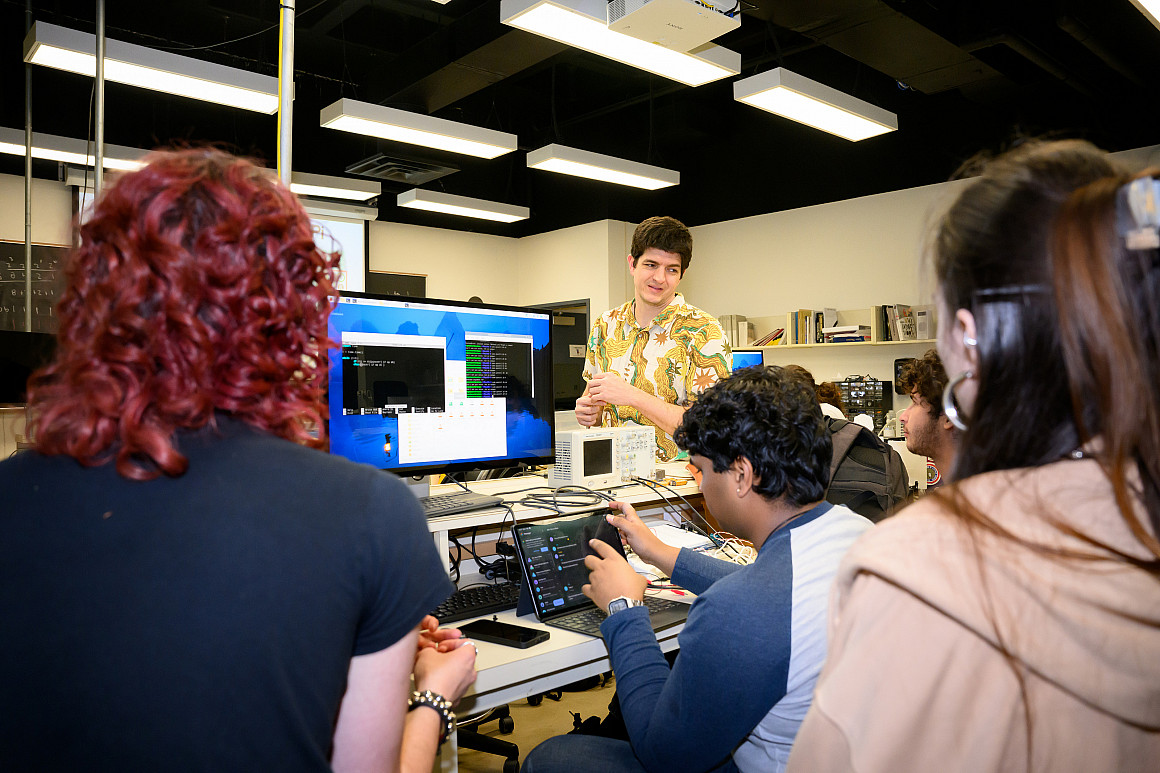 A professor and student stand at a white board.