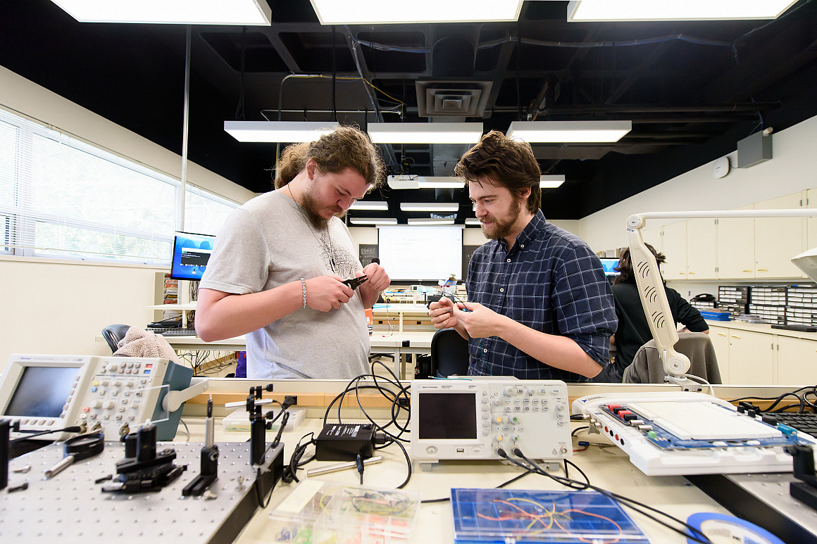 Three students sitting at a table working on research together on a computer.
