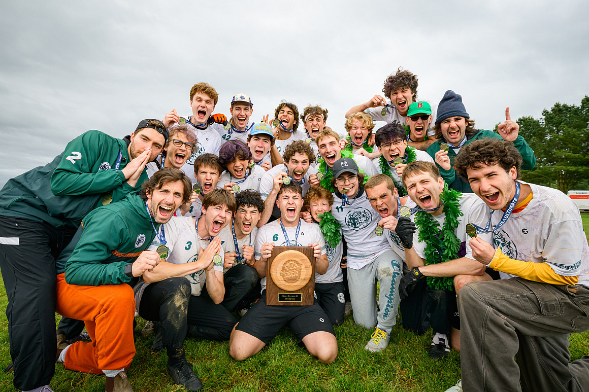 A group of student-athletes cheering and holding a trophy.