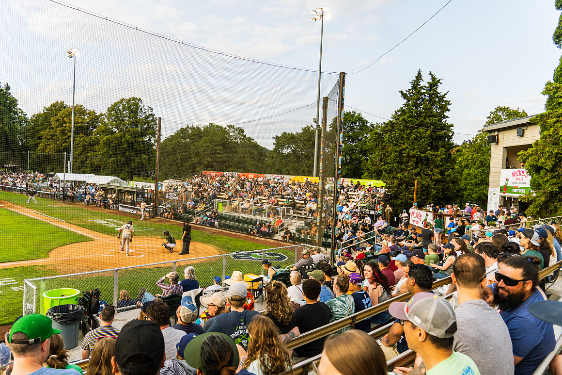 A baseball field with a large crowd of spectators sitting in seats.