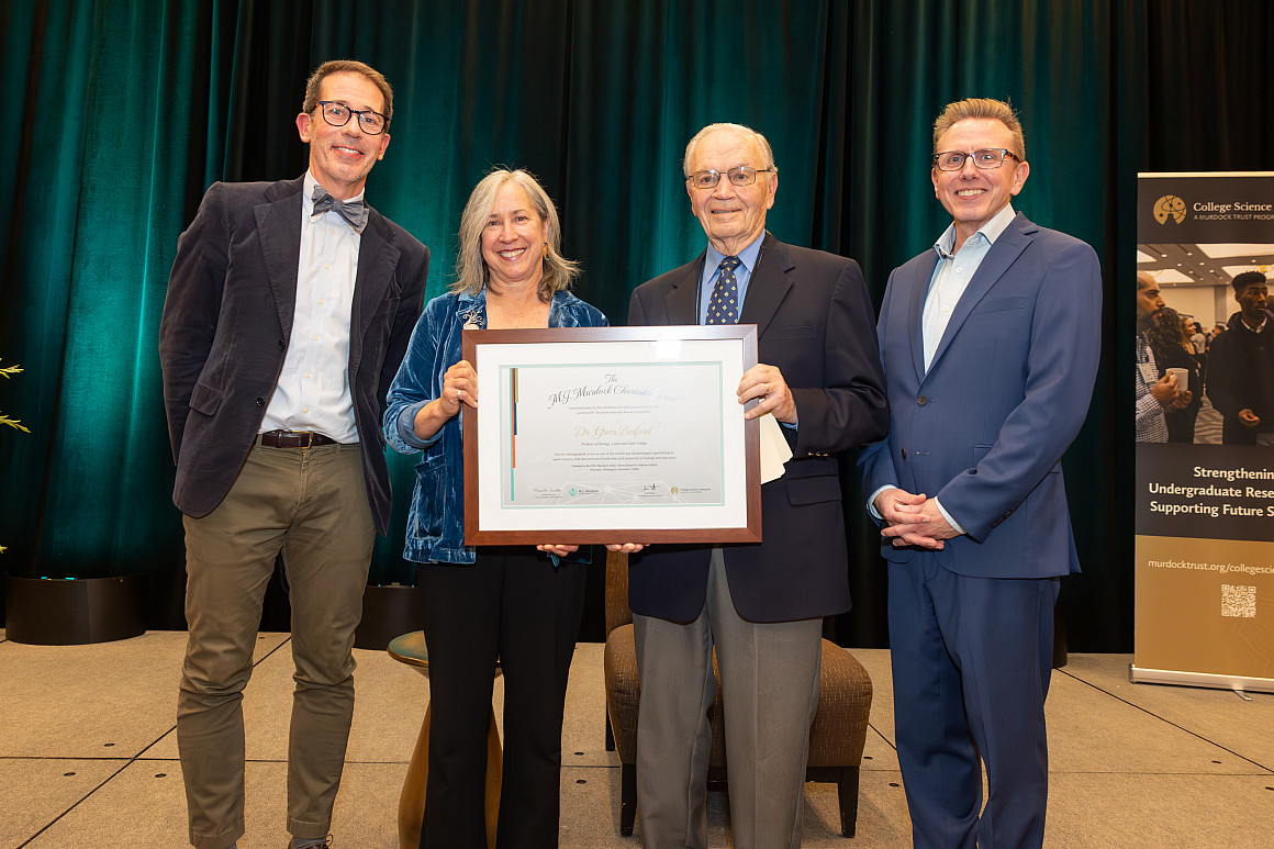 Greta posing with her award along with three other people.