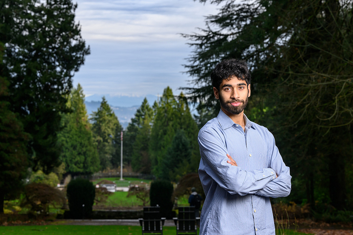 Ishan posing outside wearing a blue shirt, surrounded by green trees.