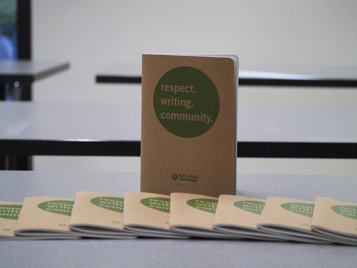 Brown journal with the words respect. writing. community in a green circle on the cover.
