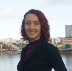 Nova smiling outside wearing a black top.