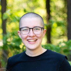 Isabel smiling outside wearing glasses and a dark top.