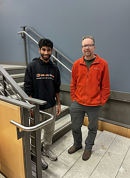 A student and professor pose together in a stairwell.