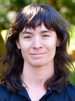 Gina smiling at the camera. She has long dark hair with bangs.