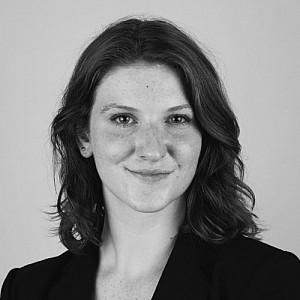A black and white headshot of Caroline, smiling at the camera.