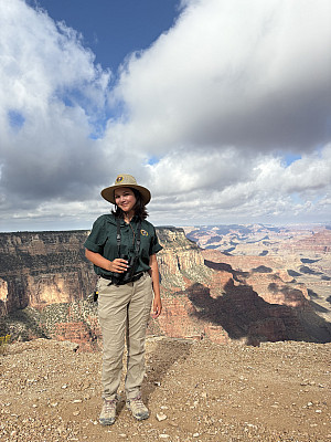 Whitney standing at the Grand Canyon, wearing a uniform and holding binoculars.