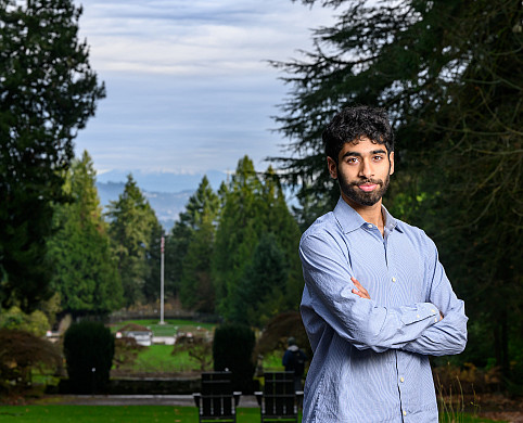 Ishan posing outside wearing a blue shirt, surrounded by green trees.