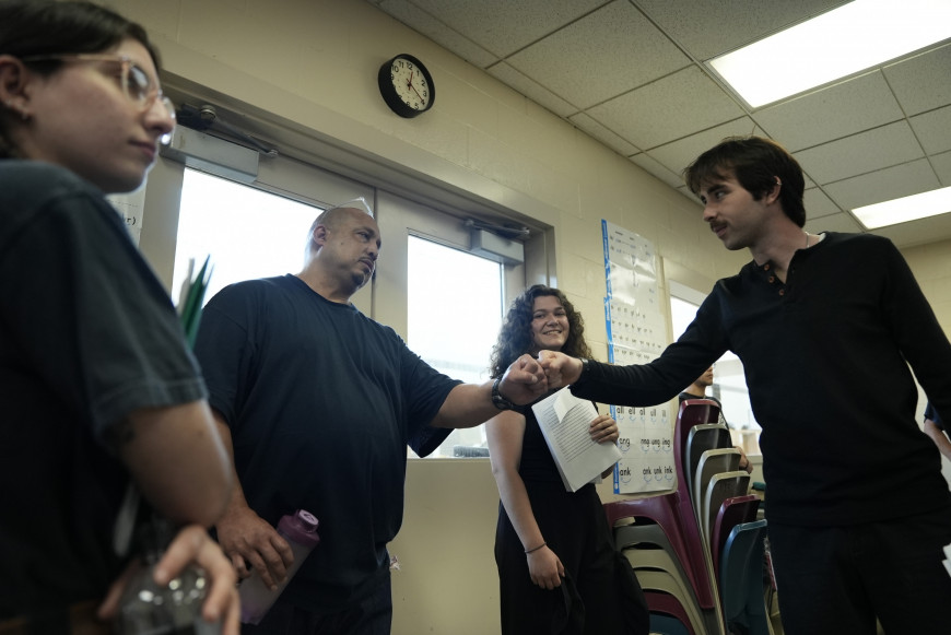 Inside and outside students fist bump each other.